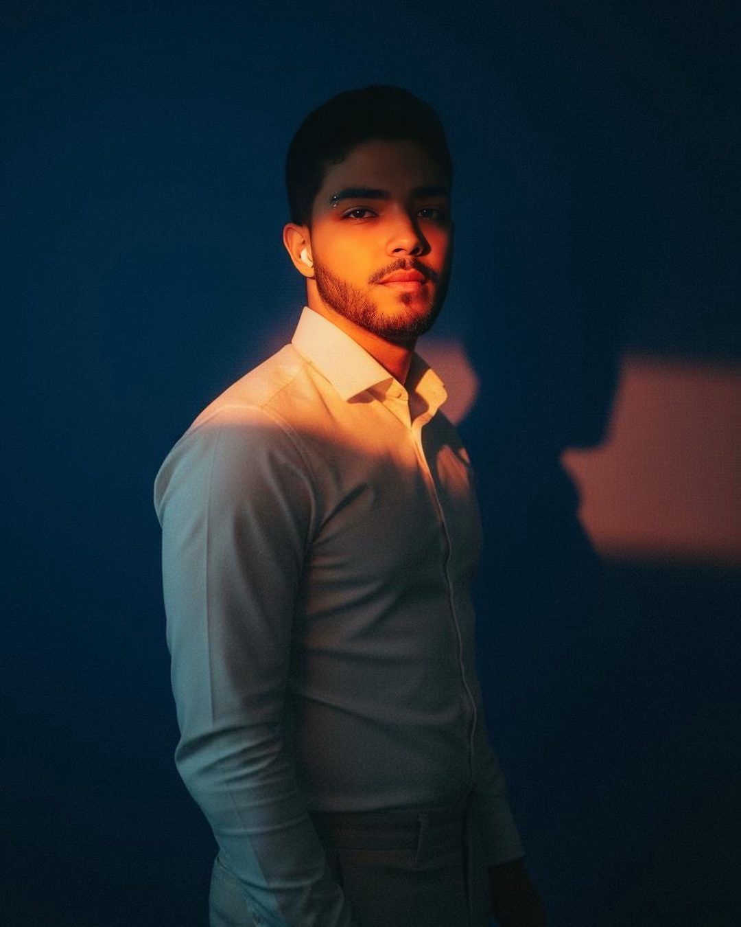 Wiliam, desenvolvedor, de camisa clara, iluminado por uma luz quente sobre fundo escuro